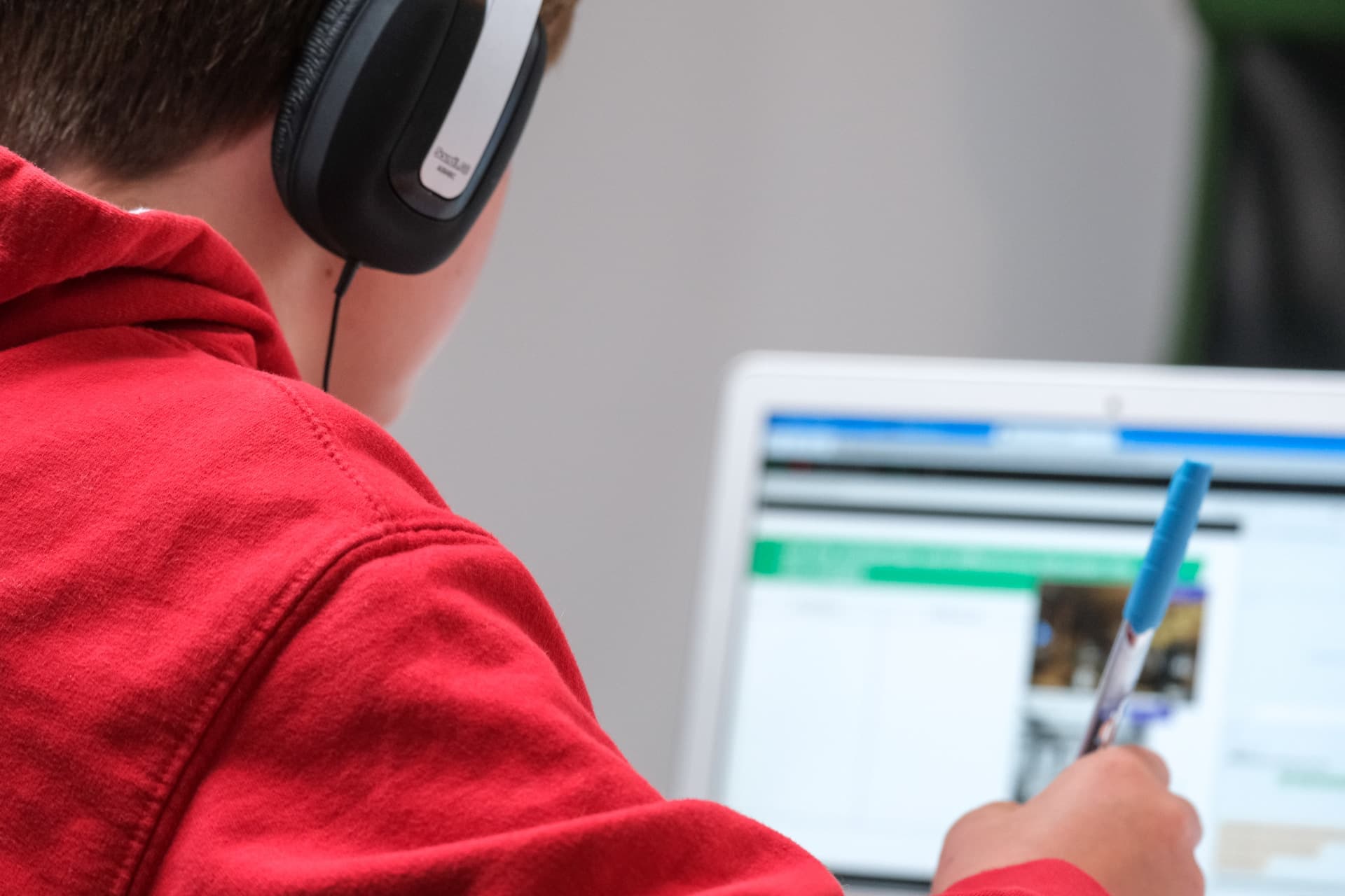 Young child sitting with tablet. He is looking at a menu of games to play.